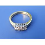 A three stone diamond ring, the square cut stones in white four-claw settings to 18ct gold shank.