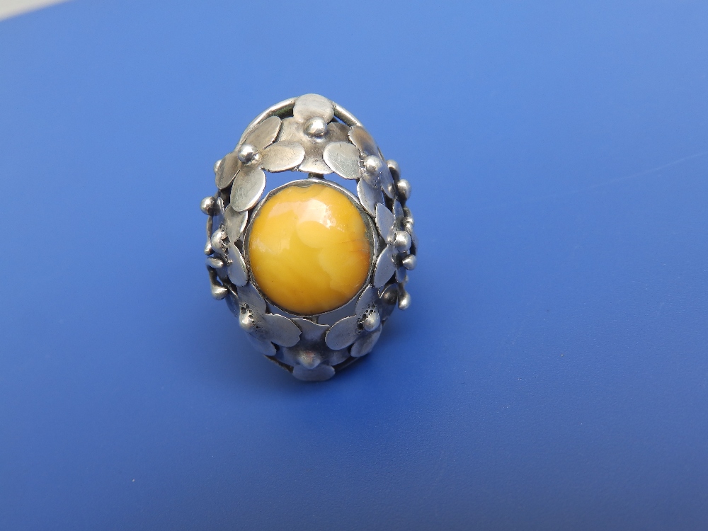 An amber set white metal cluster style ring.