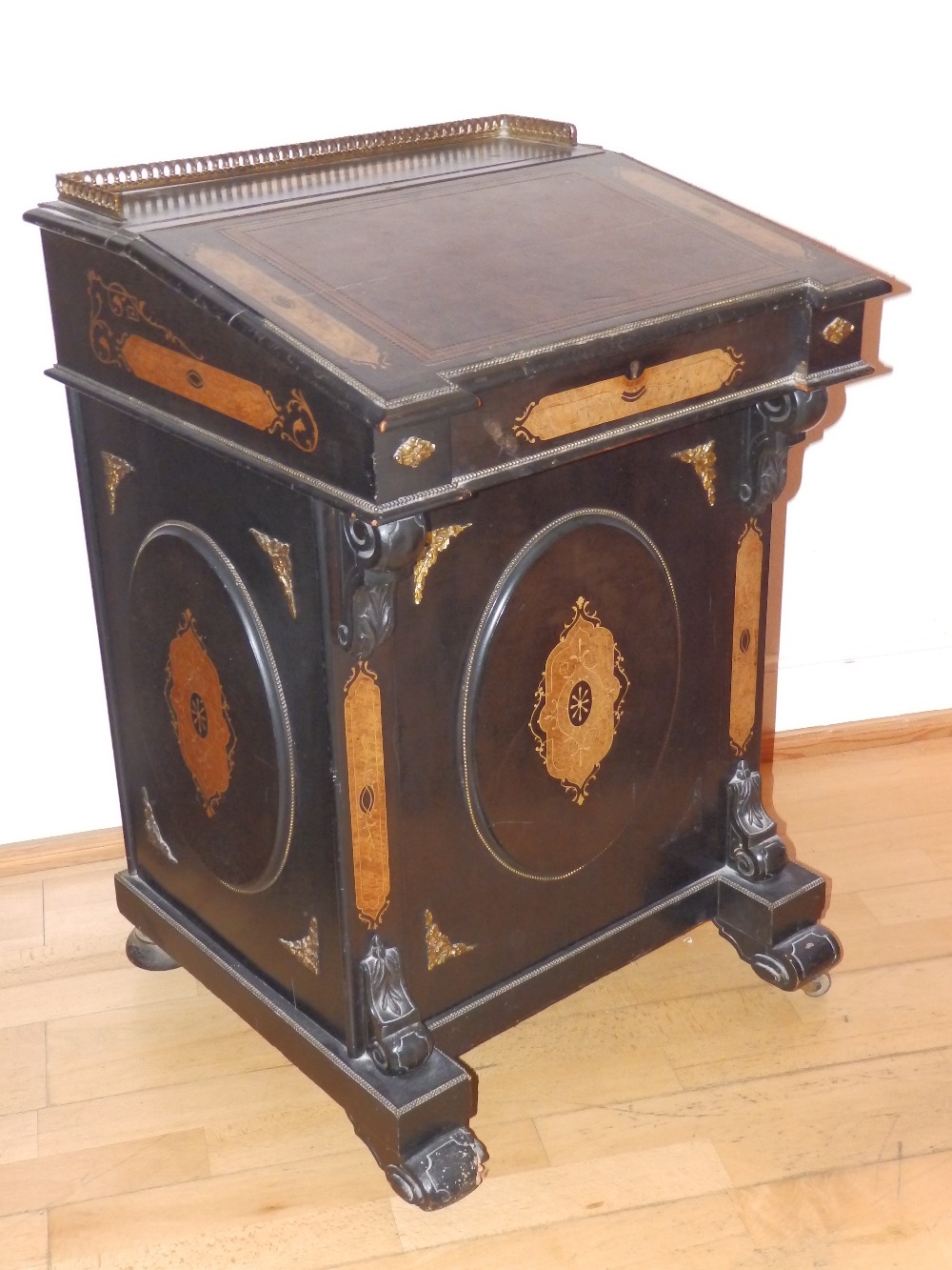 A Victorian ebonised davenport with marquetry walnut panels and ormolu mounts, the threequarter