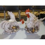 A pair of Capodimonte fighting cockerels, Heights 13” & 10”. (2)