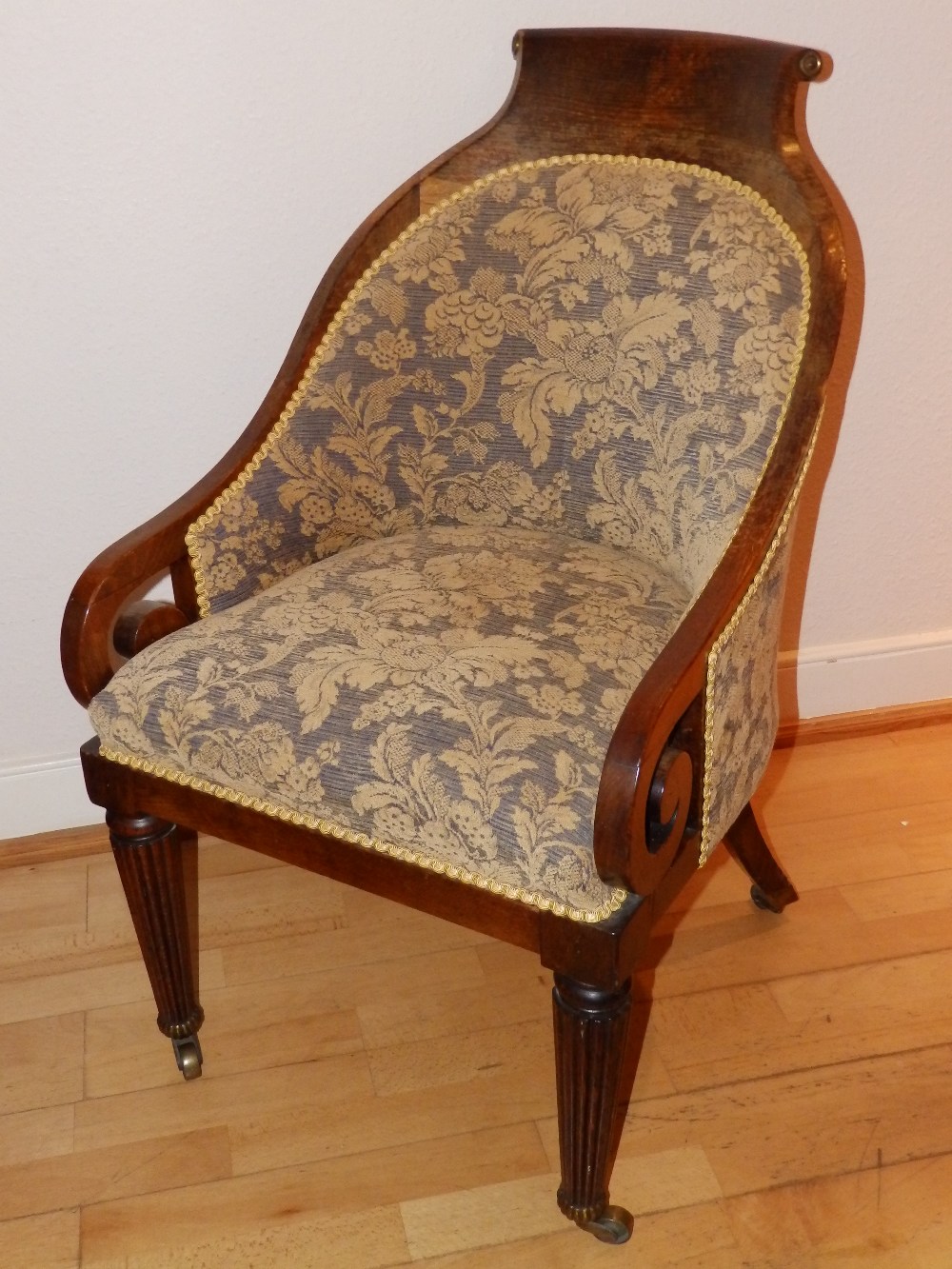 A 19thC upholstered beech bergere library chair, on reeded tapering front legs to castors, Height
