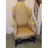 A 20thC reproduction Queen Anne style upholstered wing chair on braganza feet.
