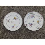 Two similar floral painted porcelain plates – interlaced 'L' marks in blue – one chipped.