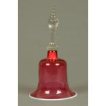 A Victorian cranberry glass bell, with wrythen moulded handle and milk glass lip.  Height 30 cm.