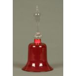 A Victorian cranberry glass bell, with clear glass handle. Height 30 cm.