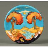 A Moorcroft plate, 2002, decorated with a river in landscape. Diameter 26 cm.