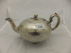A Victorian silver teapot of ovoid form with engraved foliate decoration and finial as a fruiting