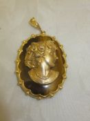 A 9 carat gold mounted tigers eye pendant set with central relief work bust of woman with flowers