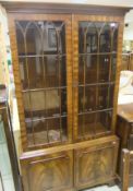 A mahogany astragal glazed display cabinet with two doors above two further doors under on bracket