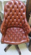 A modern button upholstered swivel office armchair in the Victorian manner raised on a splayed leg