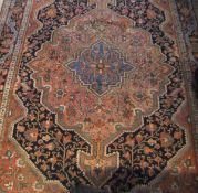 A Persian rug, the central floral decorated medallion in salmon, pale gold, cream and pale blue,