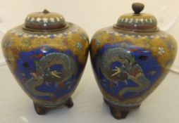 A pair of Chinese cloisonné ovoid lidded pots on three footed bases with three panels to the body,