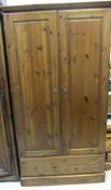 A pine Ducal two door wardrobe with single drawer below on plinth base,