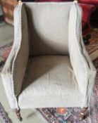 A 19th Century upholstered wing back armchair on carved and faceted front legs to casters