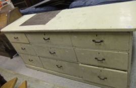 A cream painted chest of three banks of three short drawers raised on a plinth base CONDITION