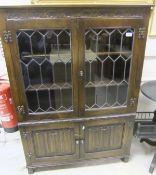 An oak display cabinet with astragal glazed doors over two cupboard doors with linen-fold