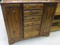 A pine Ducal two door cupboard with central bank of six graduated drawers,