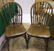 A set of four wheel and stick back dining chairs with stretchered bases and a green Lloyd Loom