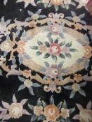 A Chinese superwash carpet in shades of pink, salmon, green, cream and blue on a black ground,