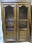 An oak two door cupboard enclosing adjustable shelves, each door with two panels of wire mesh and