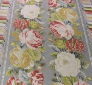 A needlepoint panel depicting floral sprays on a pale green ground within a ribbon border,