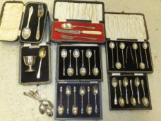 A box containing four cased sets of six silver teaspoons, one with enamel decoration,
