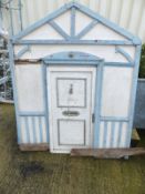 A painted child's toy wendy house with panelled sides and front door of timber framed construction