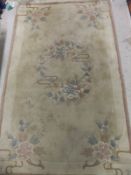 A Chinese superwash rug with floral decoration in pinks, creams and greens on a gold ground,