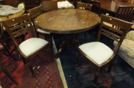 A modern hardwood circular dining table, raised on tripod base,