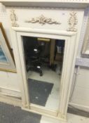 A rectangular wall mirror in a cream painted frame with applied moulding decoration
