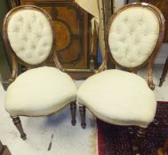 A pair of Victorian mahogany framed buttoned back salon chairs with shield shaped seats in pale