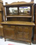 An oak Arts & Crafts mirror back sideboard, the superstructure with a pair of mirrors above a shaped