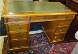 An early 20th Century oak twin pedestal desk with tooled and gilded leather insert over three