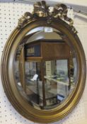 Two oval bevel edged gilt effect framed wall mirrors with ribbon pediment,