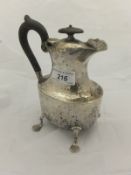 An Edwardian silver hot water jug of baluster form with ebonised handles,