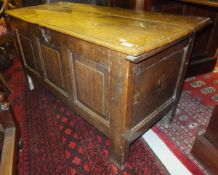 An early 18th Century oak coffer, the plank top over a three panelled front on plain supports