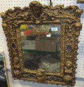 A gilt and gesso framed rectangular wall mirror with pediment as a lady's mask surrounded by