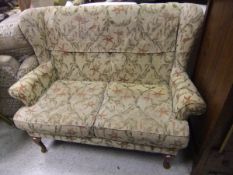 A modern cottage style two seat sofa with gold and fuschia patterned upholstery,