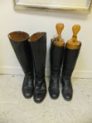 A pair of black leather riding boots with wooden trees and a further pair of riding boots