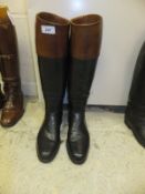 A pair of gentleman's black leather riding boots with brown tops,