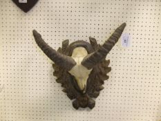 A mounted pair of Ram's horns, set on a Black Forest style carved plaque,