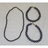 A black pearl single strand necklace and two black pearl single strand bracelets