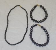 A black pearl single strand necklace and two black pearl single strand bracelets