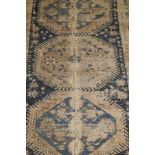 A Caucasian rug, the three central medallions in blue and taupe on a teal blue ground, within cream,