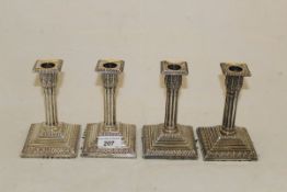 A set of four Victorian silver sheathed candlesticks of reeded form on a stepped plinth base (by