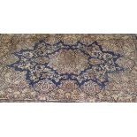 A Persian carpet with central floral medallion on a dark blue ground with all-over stylised floral