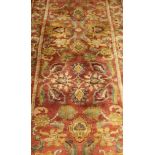 A Persian style runner with floral and foliate motifs in pale gold, red and duck egg blue,