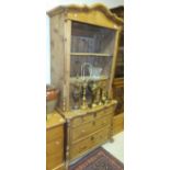 A late Victorian pine dresser with twin glazed doors enclosing shelves and fitted drawers above a