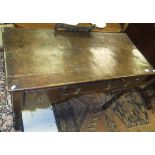 An oak hall table with three assorted drawers with brass handles to a shaped apron,