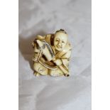 A Japanese carved ivory netsuke as a seated man with hobby horse,